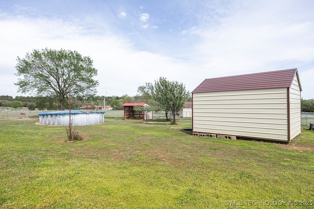 view of yard with an outdoor structure, a covered pool, and a storage unit