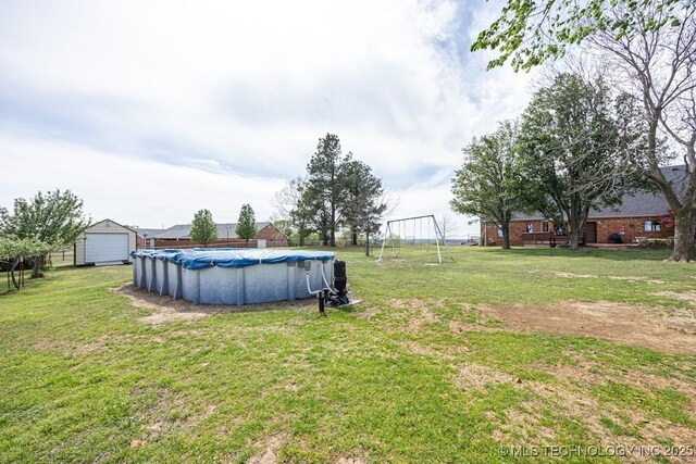 view of yard with an outbuilding, a covered pool, and a garage
