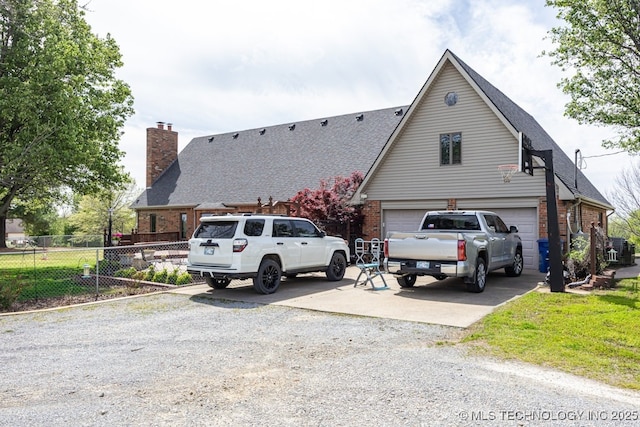 view of front of home with an attached garage, fence, concrete driveway, brick siding, and roof with shingles
