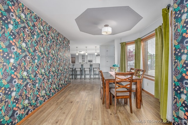 dining room featuring light wood-style flooring, baseboards, and wallpapered walls