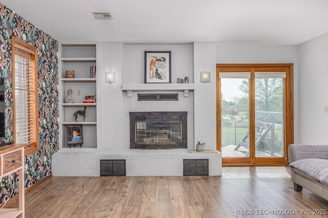 living room featuring wood finished floors, a fireplace, and visible vents