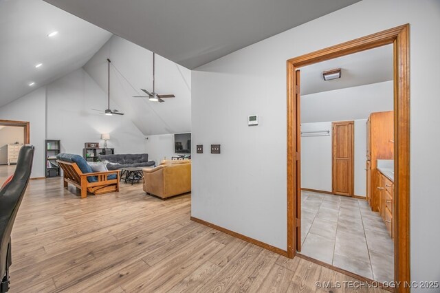 interior space with light wood-style flooring, a ceiling fan, vaulted ceiling, recessed lighting, and baseboards