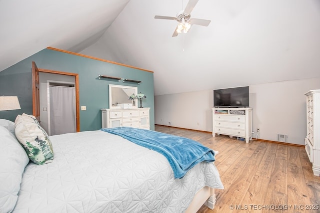 bedroom featuring ceiling fan, visible vents, vaulted ceiling, wood finished floors, and baseboards