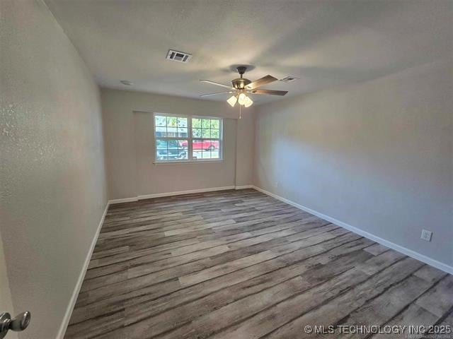 unfurnished room with visible vents, baseboards, a ceiling fan, and wood finished floors