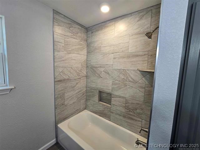 bathroom featuring shower / tub combination and baseboards