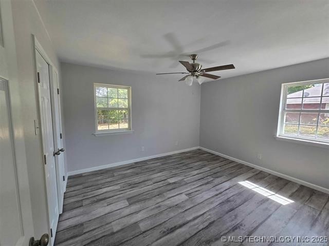 empty room featuring baseboards, a ceiling fan, and wood finished floors