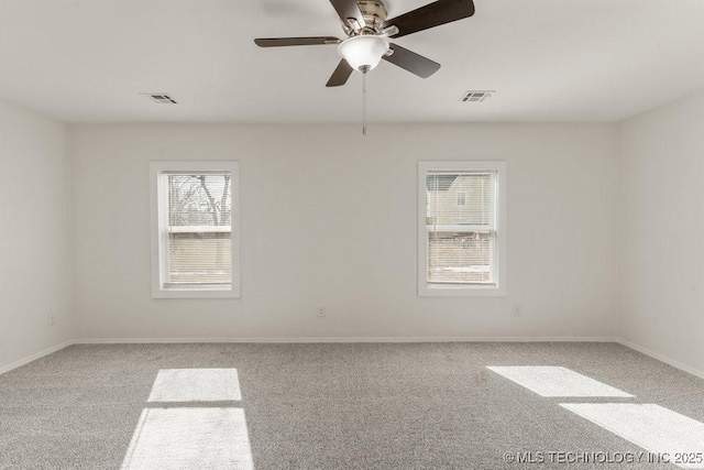 spare room with a ceiling fan, carpet, visible vents, and plenty of natural light