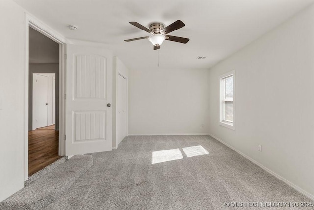 unfurnished bedroom with a ceiling fan, baseboards, carpet, and visible vents