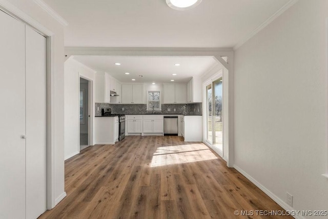 kitchen featuring white cabinets, appliances with stainless steel finishes, under cabinet range hood, light wood-style flooring, and decorative backsplash