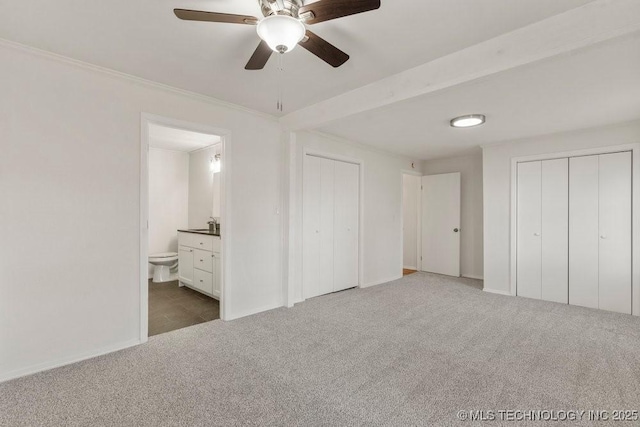 unfurnished bedroom with carpet, two closets, connected bathroom, and crown molding