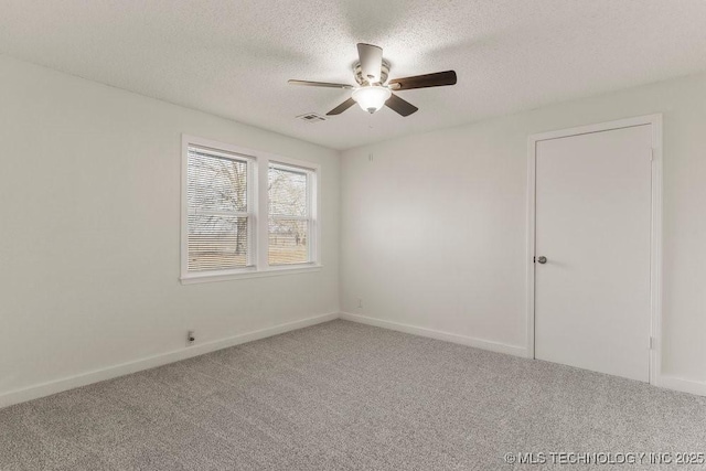 spare room with visible vents, a ceiling fan, carpet flooring, and a textured ceiling
