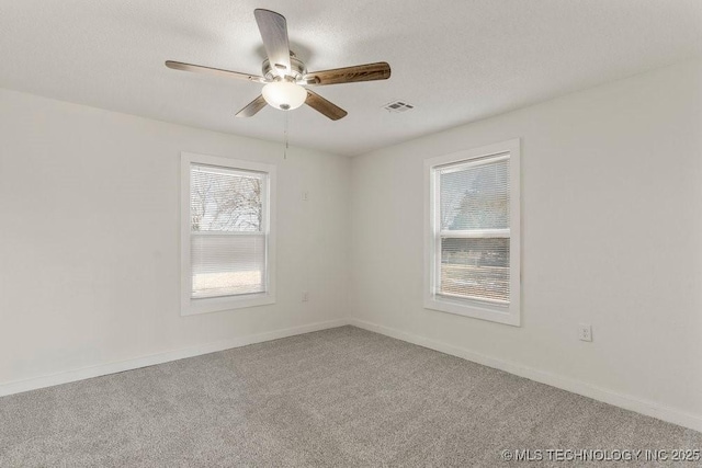 carpeted empty room featuring visible vents, ceiling fan, baseboards, and a textured ceiling