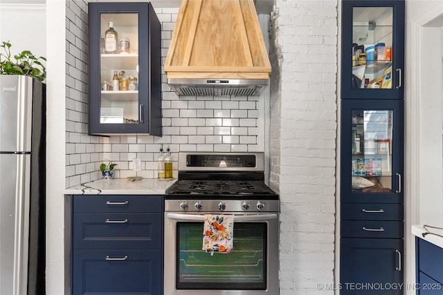 1235 S Atlanta Pl, Tulsa, OK 74104 - kitchen with glass insert cabinets, custom exhaust hood, appliances with stainless steel finishes, blue cabinets, and backsplash