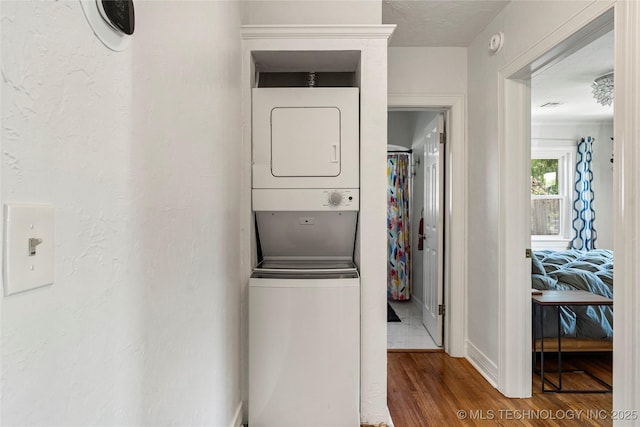 1235 S Atlanta Pl, Tulsa, OK 74104 - washroom featuring stacked washer and dryer, baseboards, laundry area, and wood finished floors