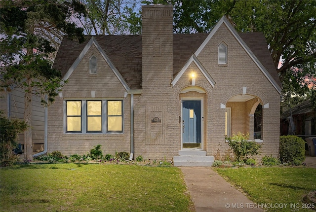 1235 S Atlanta Pl, Tulsa, OK 74104 - tudor house with a chimney, a front lawn, and brick siding