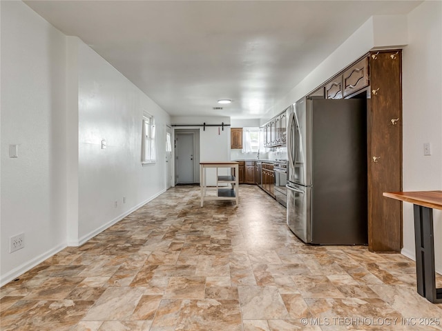kitchen featuring plenty of natural light, a barn door, stone finish flooring, and appliances with stainless steel finishes