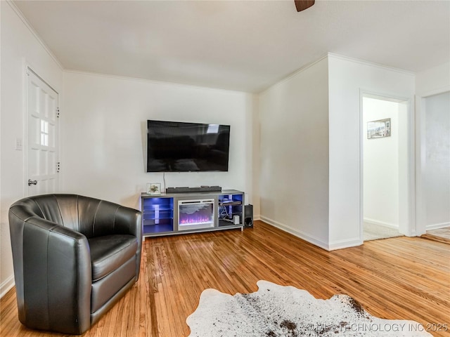 living area with baseboards, ornamental molding, and wood finished floors