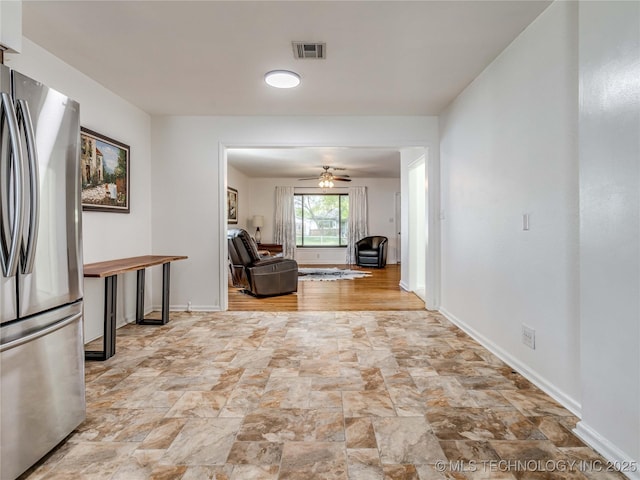 hallway featuring stone finish floor, baseboards, and visible vents