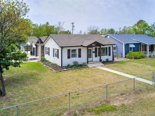 ranch-style home with a shingled roof, a front lawn, and a fenced backyard