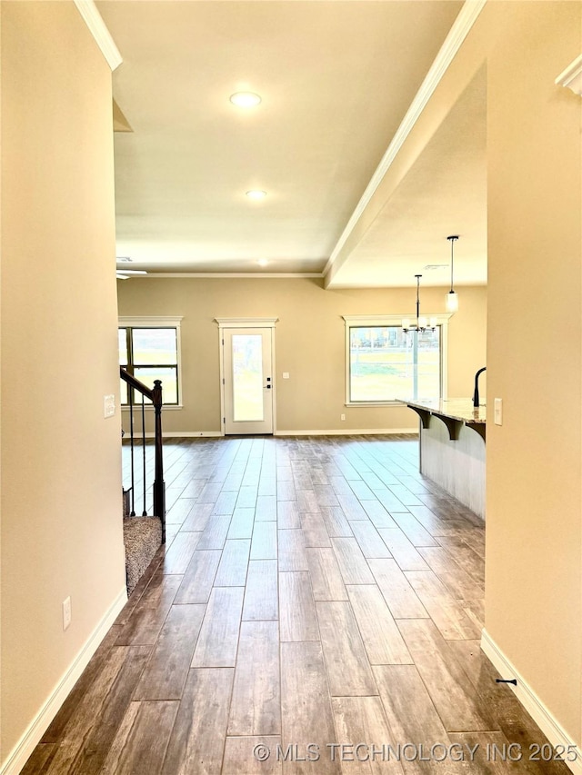interior space featuring crown molding, an inviting chandelier, wood finished floors, and baseboards