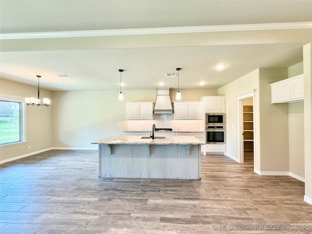 kitchen with tasteful backsplash, custom exhaust hood, appliances with stainless steel finishes, a sink, and baseboards