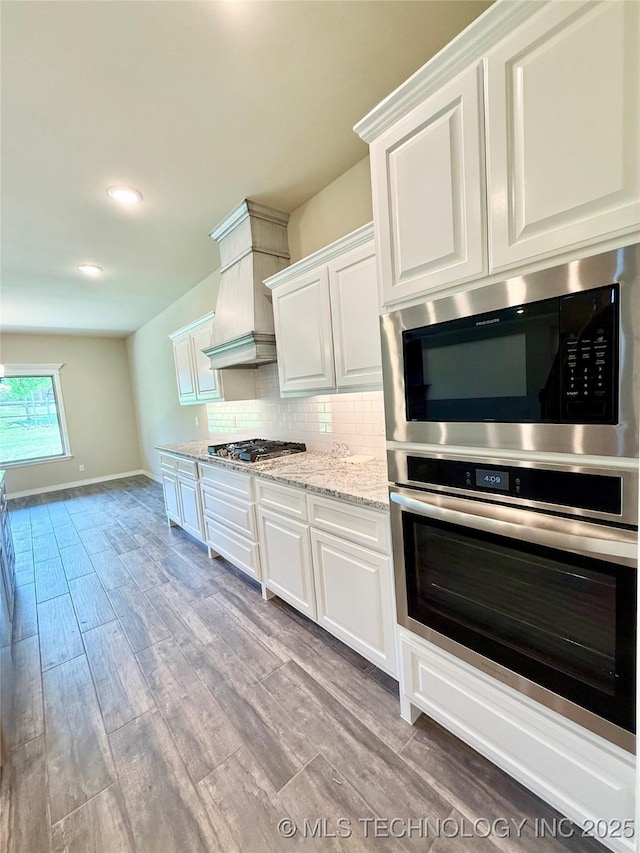kitchen featuring appliances with stainless steel finishes, light wood-style floors, decorative backsplash, and white cabinetry