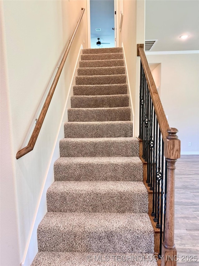 staircase with baseboards, visible vents, wood finished floors, and ornamental molding