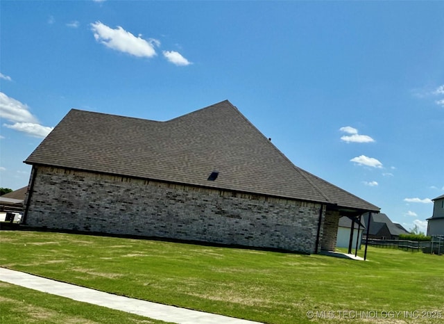 view of side of home featuring a yard, a shingled roof, and brick siding