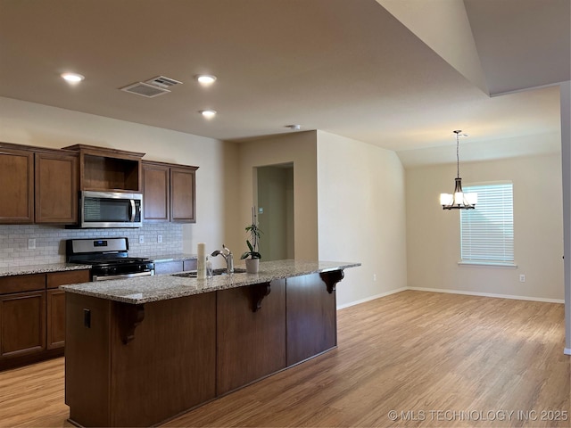 6370 E 124th Ct, Bixby, OK 74008 - kitchen featuring appliances with stainless steel finishes, a kitchen breakfast bar, tasteful backsplash, light wood-style floors, and recessed lighting