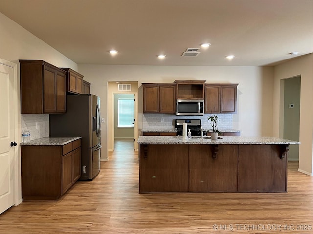 6370 E 124th Ct, Bixby, OK 74008 - kitchen with appliances with stainless steel finishes, decorative backsplash, light wood finished floors, light stone counters, and recessed lighting