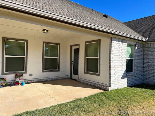 6370 E 124th Ct, Bixby, OK 74008 - doorway to property with a shingled roof, a patio area, brick siding, and a lawn