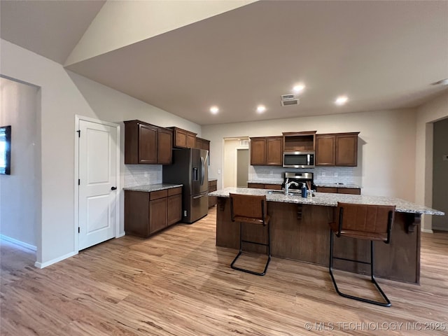 6370 E 124th Ct, Bixby, OK 74008 - kitchen with appliances with stainless steel finishes, backsplash, light wood-style floors, a breakfast bar area, and recessed lighting