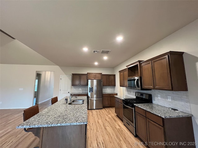 6370 E 124th Ct, Bixby, OK 74008 - kitchen with stainless steel appliances, light wood finished floors, dark brown cabinets, a kitchen breakfast bar, and tasteful backsplash