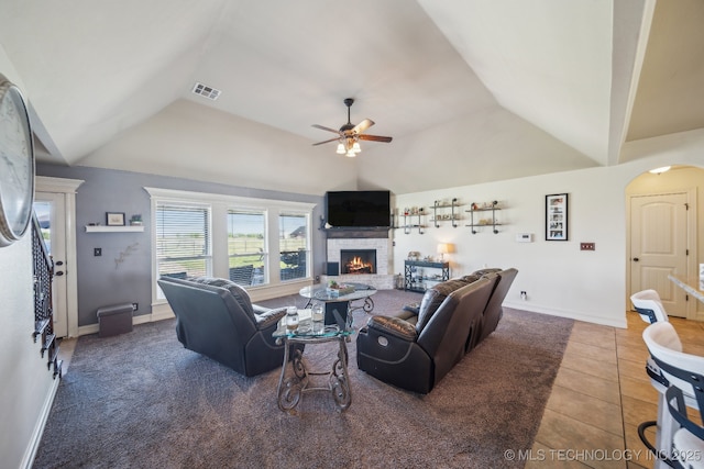 6199 E 144th St N, Collinsville, OK 74021 - living area with lofted ceiling, a ceiling fan, a stone fireplace, tile patterned floors, and arched walkways