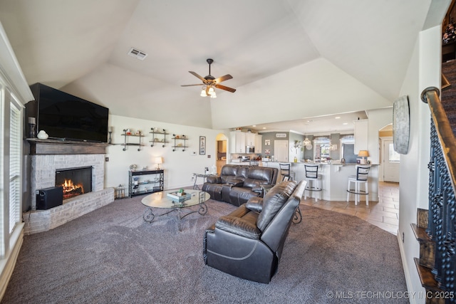 6199 E 144th St N, Collinsville, OK 74021 - living room featuring a warm lit fireplace, lofted ceiling, a ceiling fan, and light colored carpet