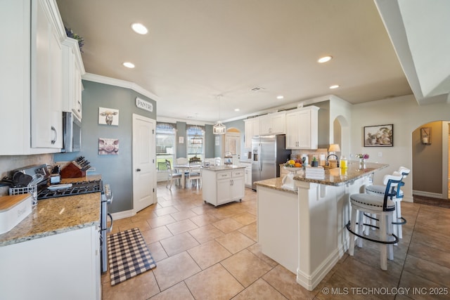 6199 E 144th St N, Collinsville, OK 74021 - kitchen with arched walkways, appliances with stainless steel finishes, recessed lighting, decorative backsplash, and white cabinets