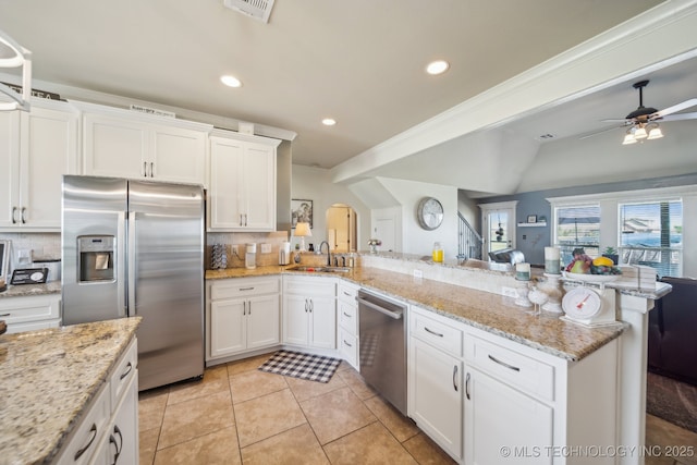 6199 E 144th St N, Collinsville, OK 74021 - kitchen featuring stainless steel appliances, a peninsula, arched walkways, ceiling fan, and backsplash