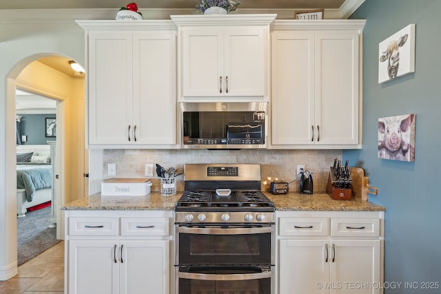6199 E 144th St N, Collinsville, OK 74021 - kitchen with stainless steel appliances, arched walkways, and white cabinets
