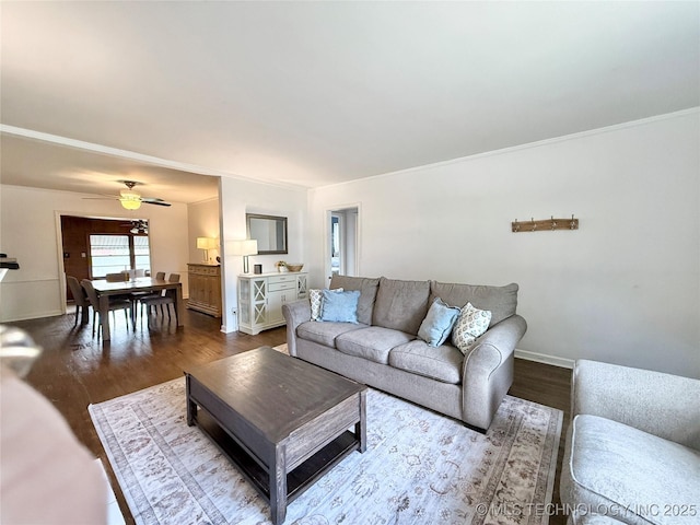 living area featuring baseboards, a ceiling fan, and dark wood finished floors