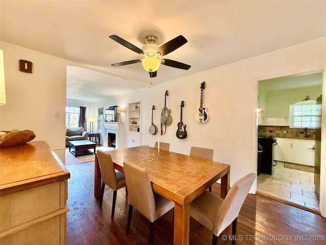 dining room with ornamental molding, a ceiling fan, wood finished floors, and a fireplace