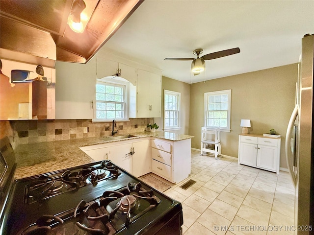 kitchen featuring freestanding refrigerator, a sink, gas stove, and a healthy amount of sunlight