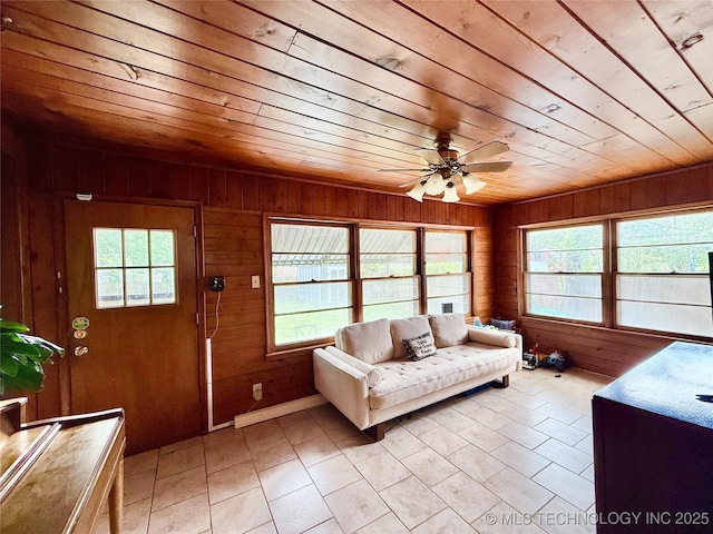 living room with wooden walls, a ceiling fan, wooden ceiling, and light tile patterned flooring