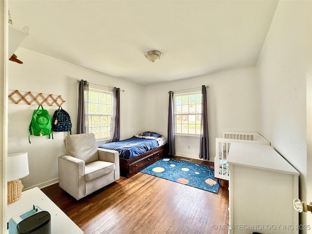 bedroom featuring wood finished floors, baseboards, and multiple windows