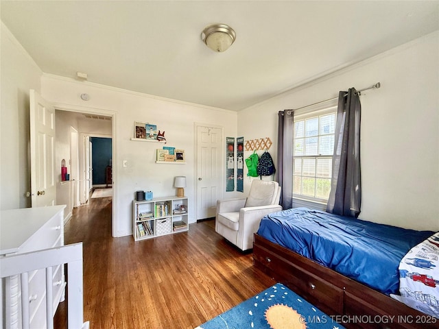 bedroom with wood finished floors and ornamental molding