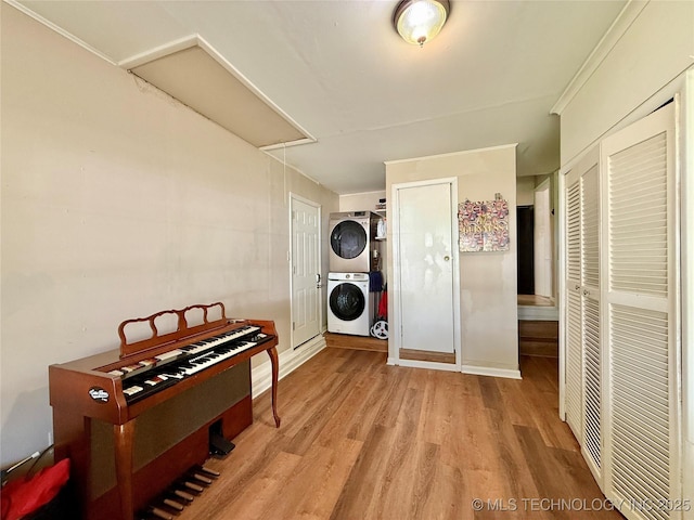 hall featuring light wood-style flooring, attic access, and stacked washer and clothes dryer