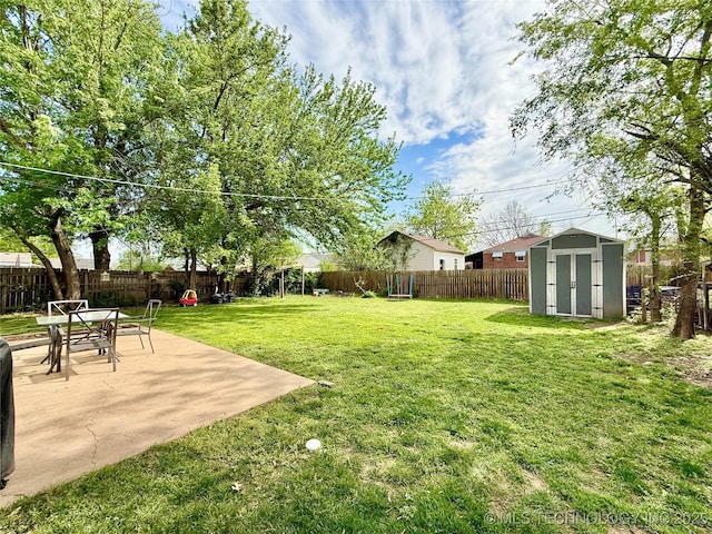 view of yard with a storage shed, a fenced backyard, a patio, and an outbuilding