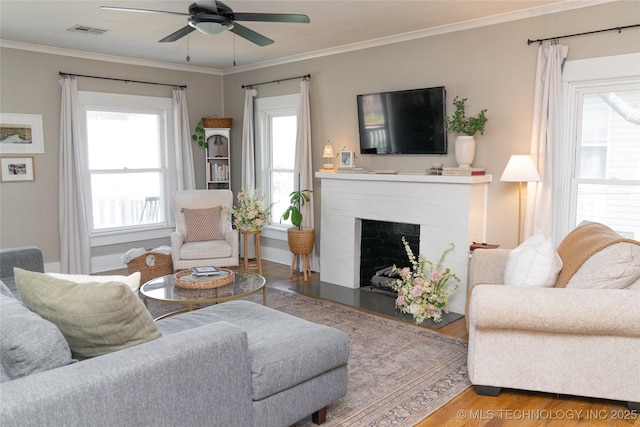 511 N Main St, Sand Springs, OK 74063 - living room with wood finished floors, healthy amount of natural light, a ceiling fan, a brick fireplace, and crown molding