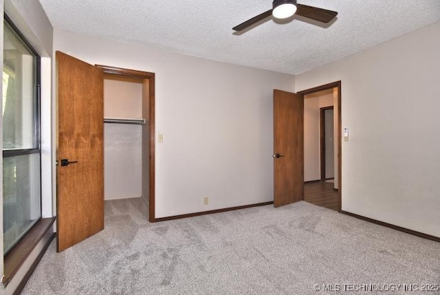 unfurnished bedroom with a spacious closet, carpet flooring, and a textured ceiling