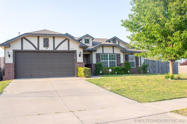 tudor home featuring brick siding, stucco siding, a front yard, and a garage