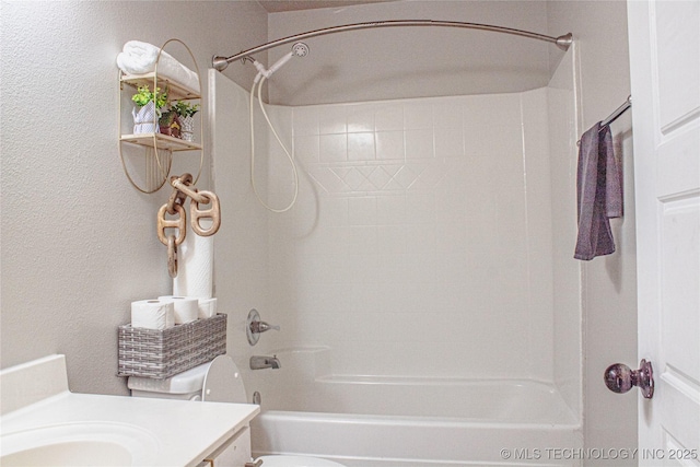 full bathroom with toilet, a textured wall, vanity, and tub / shower combination